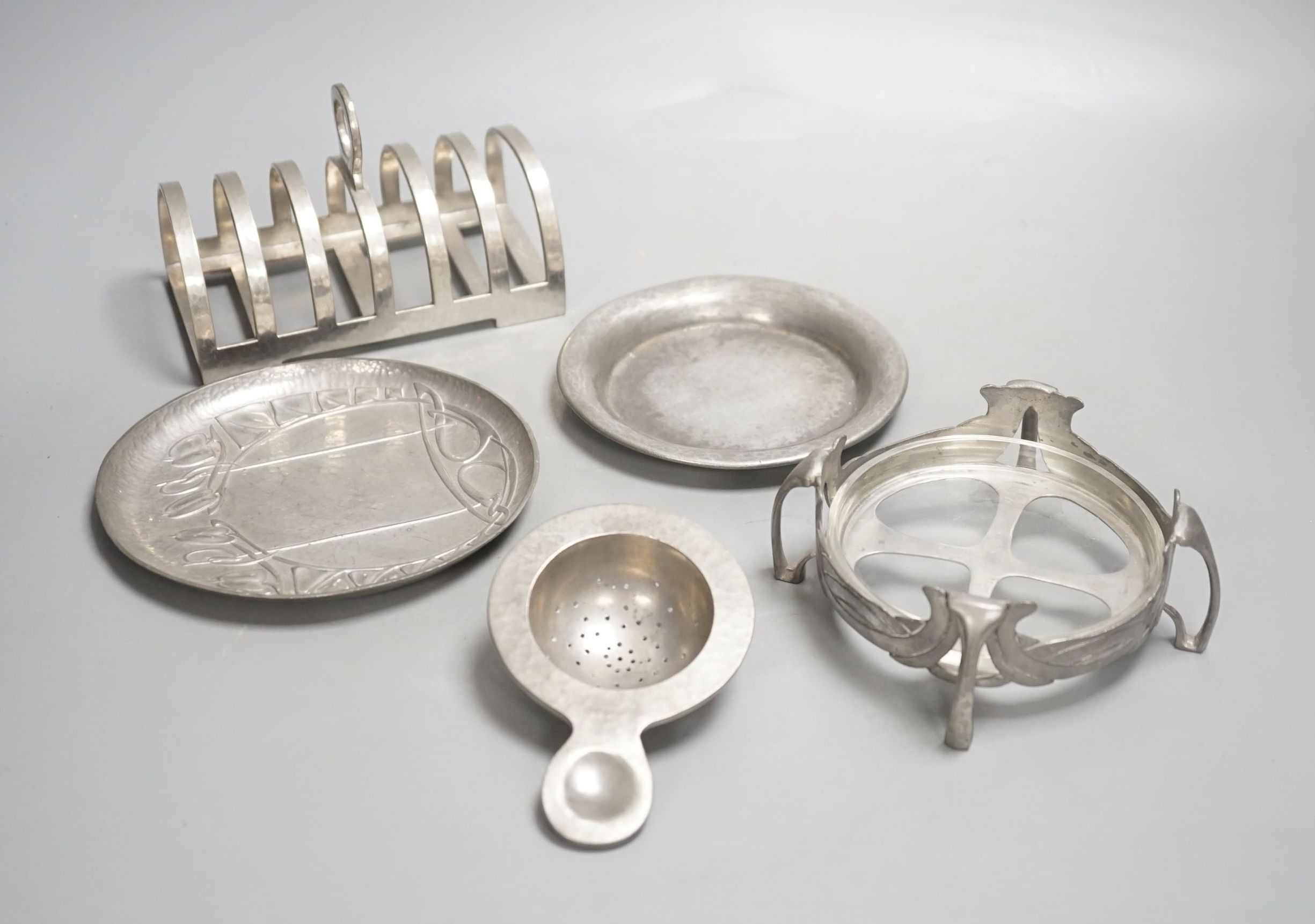 A Tudric seven bar toastrack, three Tudric serving dishes and a Tudric tea strainer, toast rack length 13.5cm